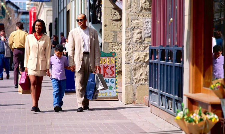 Family carrying shopping bags, walking on city street